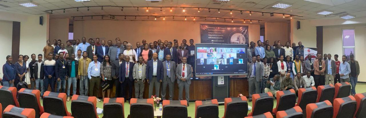 Full auditorium with participants and virtual attendees